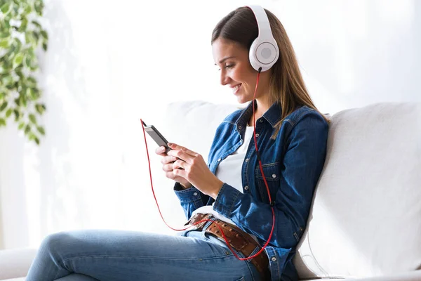 Mulher bonita ouvindo música com telefone celular em casa . — Fotografia de Stock