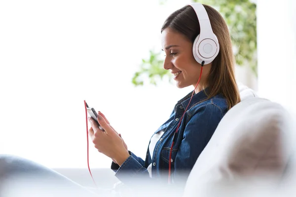 Mulher bonita ouvindo música com telefone celular em casa . — Fotografia de Stock