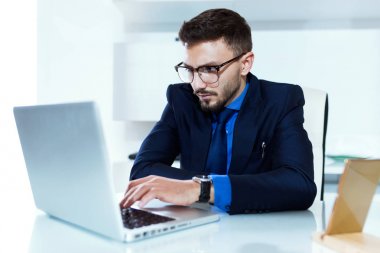 Yakışıklı genç işadamı ofiste dizüstü bilgisayar ile çalışma.