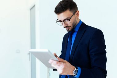 Yakışıklı genç işadamı ofiste dijital tablet ile çalışma.