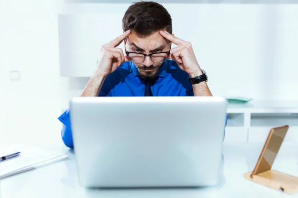 Bello giovane uomo d'affari concentrato mentre lavora con il computer portatile in ufficio . — Foto Stock