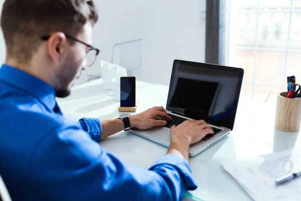 Bonito jovem empresário trabalhando com laptop no escritório . — Fotografia de Stock