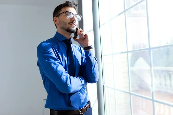 Knappe jonge zakenman met behulp van zijn mobiele telefoon in het kantoor. — Stockfoto
