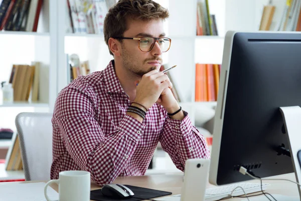 Bonito jovem empresário usando seu laptop no escritório . — Fotografia de Stock