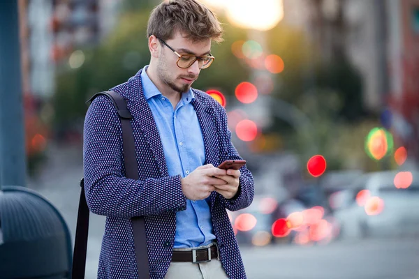 Όμορφος νεαρός επιχειρηματίας χρησιμοποιώντας το κινητό του τηλέφωνο στο δρόμο. — Φωτογραφία Αρχείου