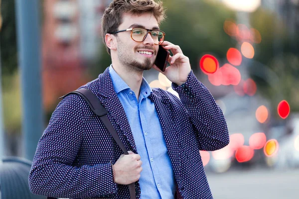 Beau jeune homme d'affaires utilisant son téléphone portable dans la rue . — Photo