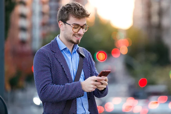 Beau jeune homme d'affaires utilisant son téléphone portable dans la rue . — Photo