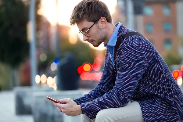 Knappe jonge zakenman met behulp van zijn mobiele telefoon in de straat. — Stockfoto