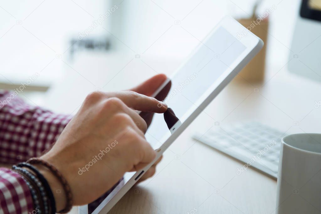 Handsome young businessman using his digital tablet in the office.