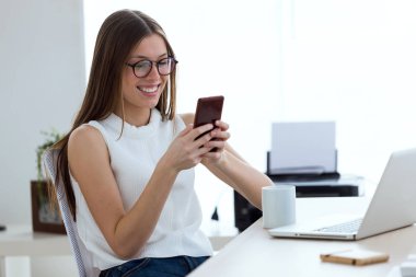 Ofiste cep telefonu kullanan iş genç kadın.