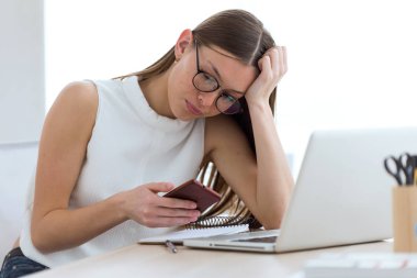 Ofiste cep telefonu kullanan iş genç kadın.