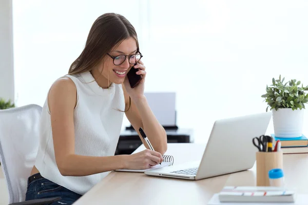 Mujer joven de negocios usando su teléfono móvil en la oficina . —  Fotos de Stock