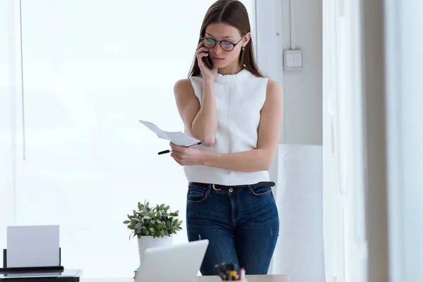 Бізнес молода жінка використовує свій мобільний телефон в офісі . — стокове фото