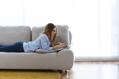 Evdeki bilgisayarını kullanan güzel bir genç kadın..