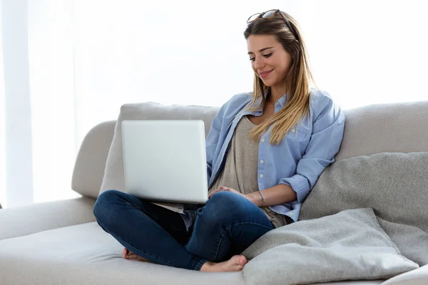 Vacker ung kvinna använder sin bärbara dator hemma. — Stockfoto