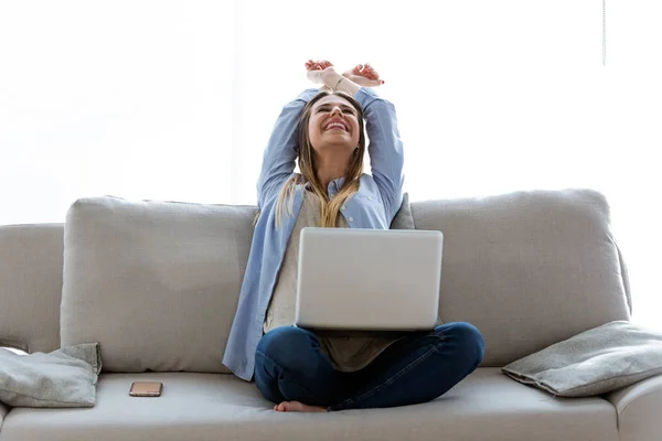 Mulher bonita comemorando um sucesso enquanto trabalhava com laptop em casa . — Fotografia de Stock