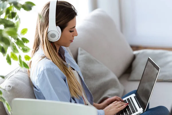 Mulher bonita ouvindo música com laptop em casa . — Fotografia de Stock