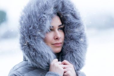 Güzel genç kadın yan ormanda kar ile bir kış gününde arıyor.