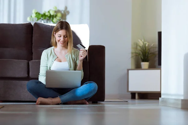 Krásná mladá žena pomocí její laptop pro online nakupování u vás doma. — Stock fotografie