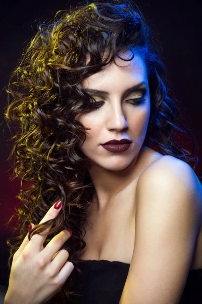 Mulher bonita com cabelo encaracolado e profissional compõem posando no estúdio . — Fotografia de Stock