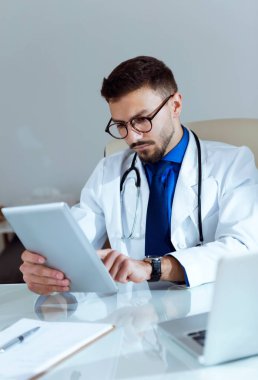 Onun dijital tablet ofisteki çalımakta kendine güvenen erkek doktor.