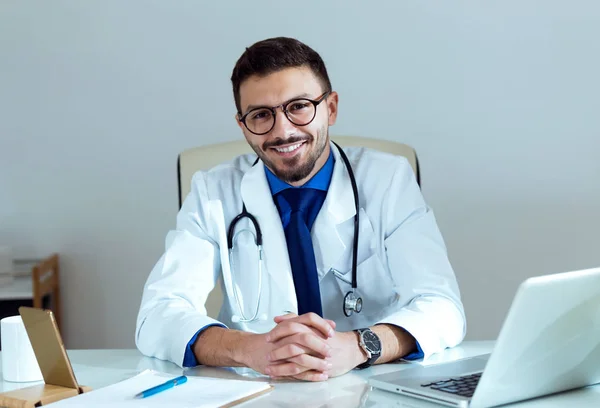 Jistý muž Doktor s úsměvem a při pohledu na fotoaparát v kanceláři. — Stock fotografie