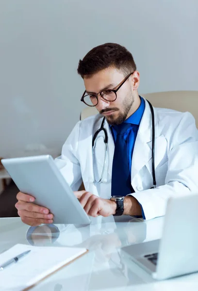 Médico varón de confianza trabajando con su tableta digital en la oficina . —  Fotos de Stock