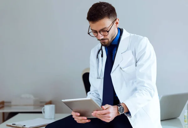 Médecin masculin confiant travaillant avec sa tablette numérique au bureau . — Photo