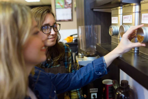 Beautiful young woman customer choosing tea sold by weight in organic shop. — Stock Photo, Image