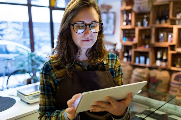 Belle jeune vendeuse utilisant sa tablette numérique dans un magasin bio . — Photo