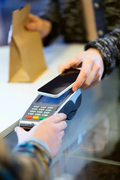 Kundin nutzt ihr Smartphone für mobiles Bezahlen mit elektronischem Lesegerät. — Stockfoto
