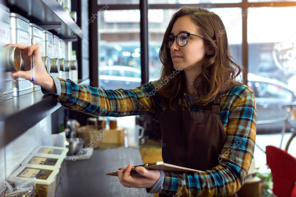 Beautiful young saleswoman doing inventory in a retail store selling coffee.