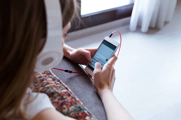 Hermosa mujer joven escuchando música con teléfono móvil en casa . —  Fotos de Stock