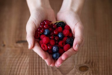 Yaban mersini ve ahududu ahşap arka plan üzerinde tutan bazı eller.