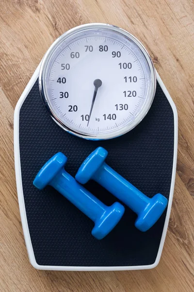 Mancuernas azules en la parte superior de la escala de peso sobre fondo de madera en el gimnasio . — Foto de Stock