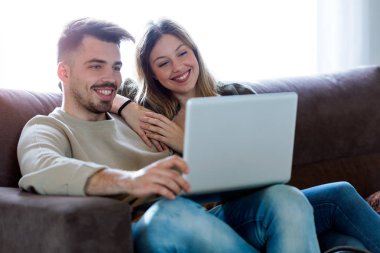 Güzel genç çift istimal onların laptop vasıl ev gülümseyen.