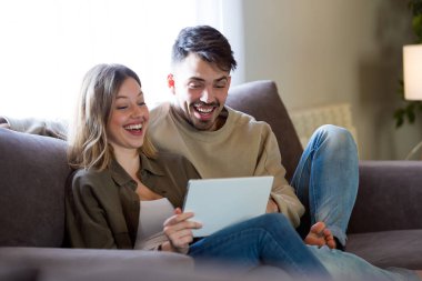 Güzel genç çift istimal onların dijital tablet vasıl ev gülümseyen.