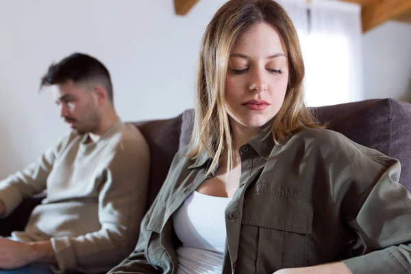 Arga unga paret sitter på soffan tillsammans och ser att motsatta sidor hemma. — Stockfoto