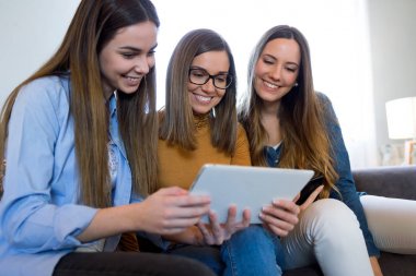 Üç mutlu güzel kadın evde dijital tablet kullanma.