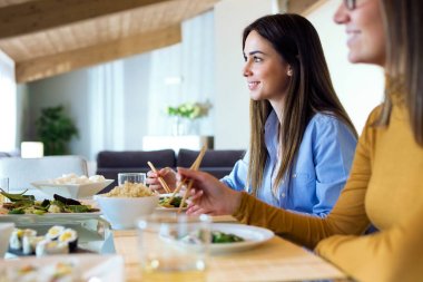 İki güzel genç kadın evde Japon yemek yeme.