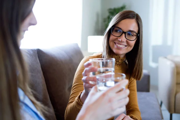 Deux belles femmes heureuses trinquant avec un verre d'eau à la maison — Photo