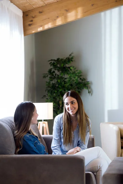 Två glada unga kvinnliga vänner samtala i vardagsrummet hemma — Stockfoto