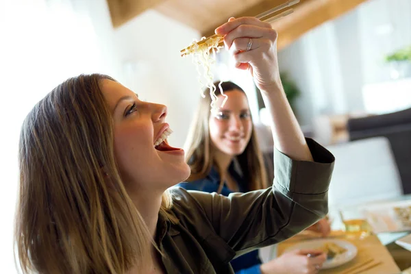 Zwei schöne junge Frauen essen japanisches Essen zu Hause. — Stockfoto