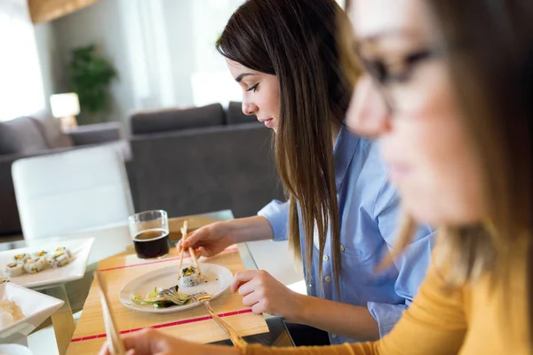 İki güzel genç kadın evde Japon yemek yeme.