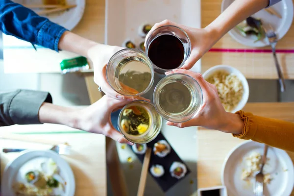 Fyra unga kvinnor som grillas med vin medan man äter hemma. — Stockfoto