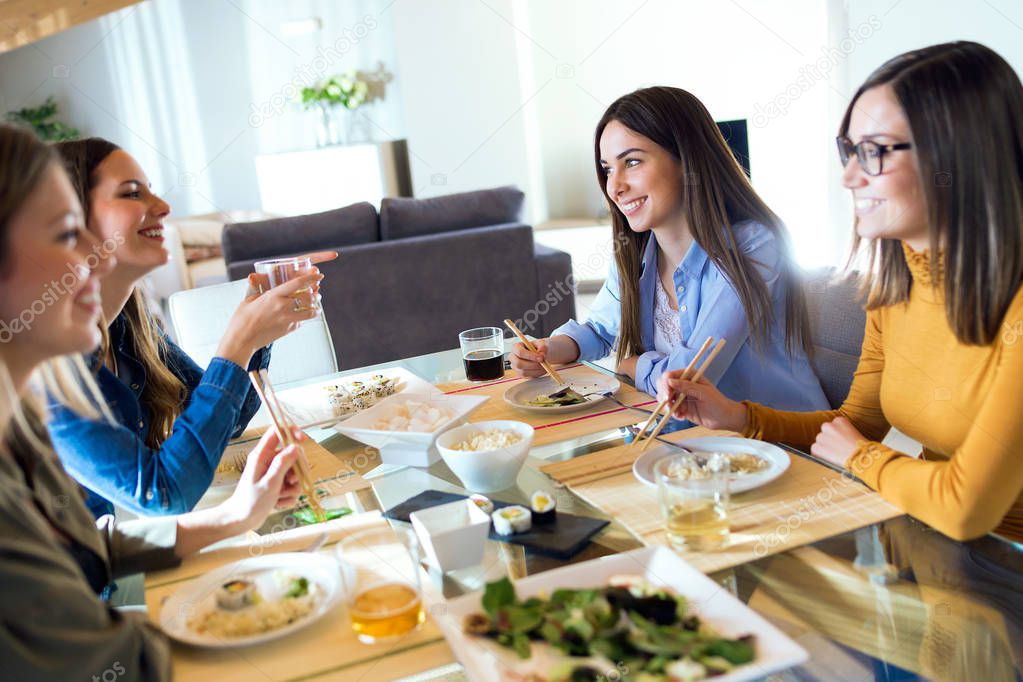 Four beautiful young women eating japanese food at home.