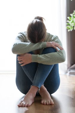 Mutsuz yalnız ve depresyonda genç kadın evde bacaklarının arasına yüzünü gizleme.