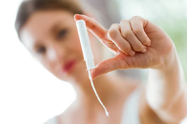 Pretty young woman holding and looking tampon in the bathroom. — Stock Photo, Image