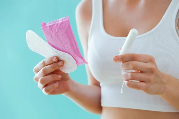 Mujer joven con una compresa menstrual y un tampón sobre fondo azul . —  Fotos de Stock