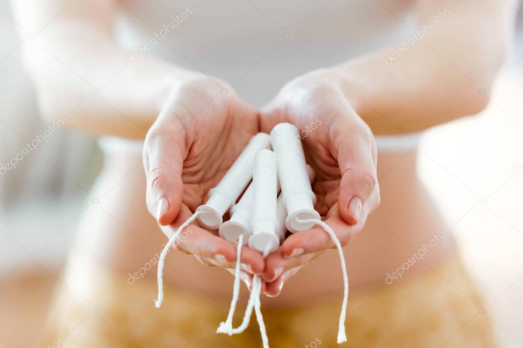 Hands of a woman holding some tampons.